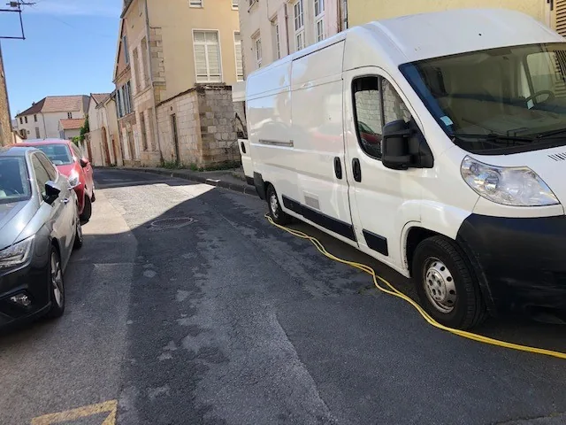 Camion d’intervention stationné devant un immeuble, câble d’alimentation déroulé jusqu’au logement traité