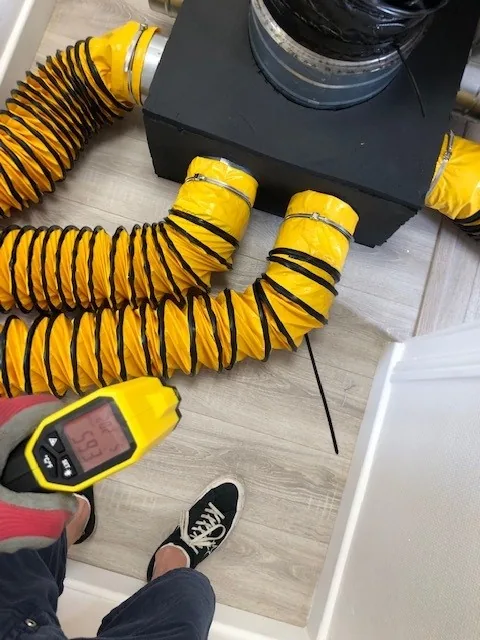 Générateur de chaleur relié à des gaines jaunes, avec une sonde de température posée au sol